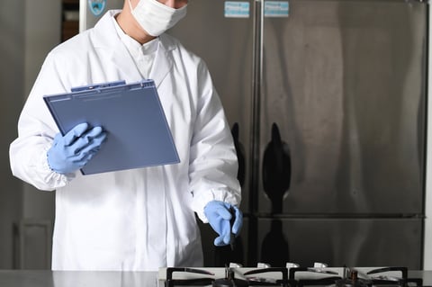 Asian man wearing sanitary clothes inspecting kitchen equipment