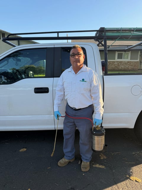 Male service technician in white shirt and glasses standing in front of white work van on sunny day